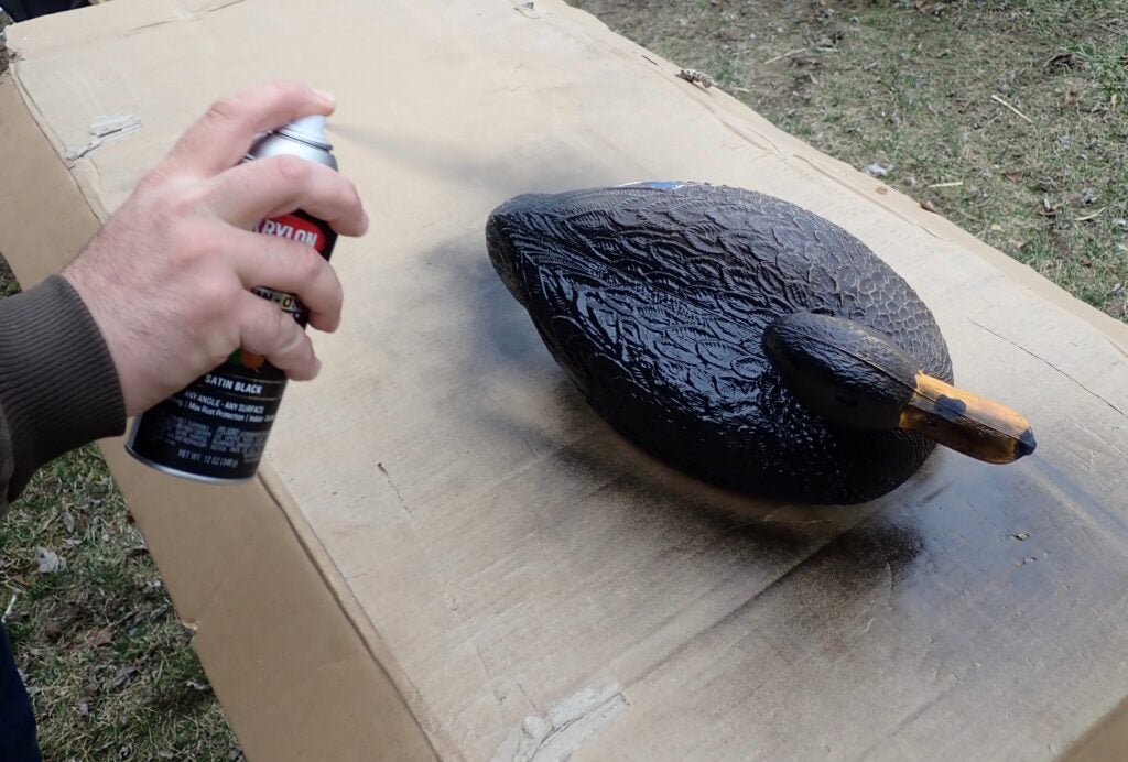 Hand spray painting a duck decoy.