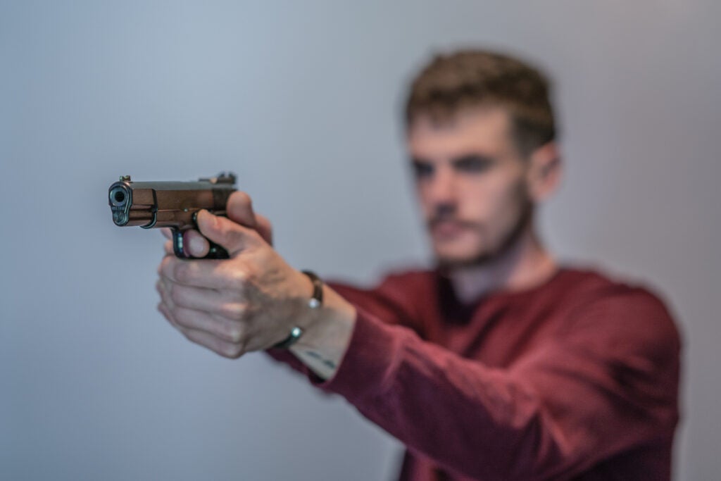 Batt Mann practices shooting a handgun.