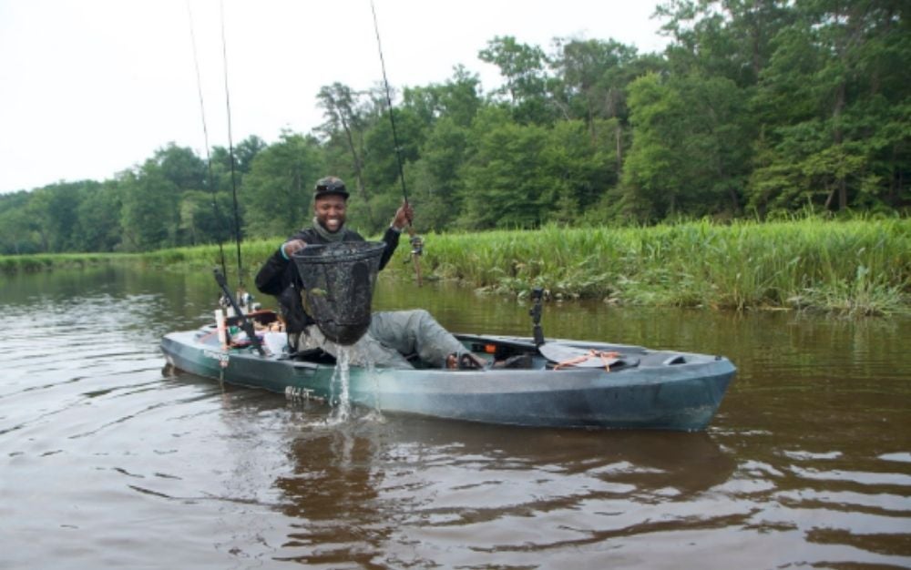 Fisherman with a net in the Old Town Topwater 120 kayak