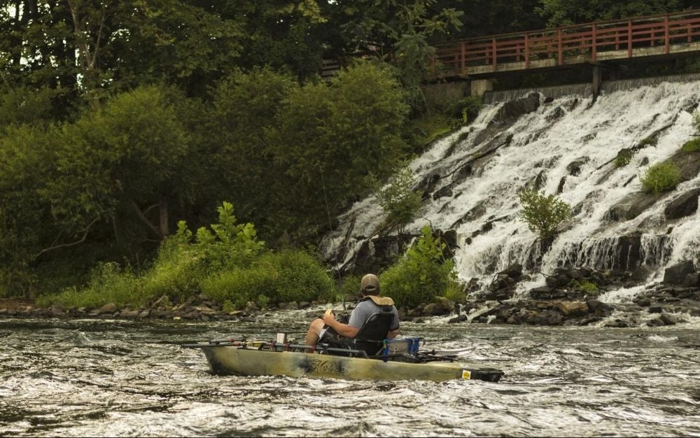 Person sitting on a Hobie kayak and fishing on the river.