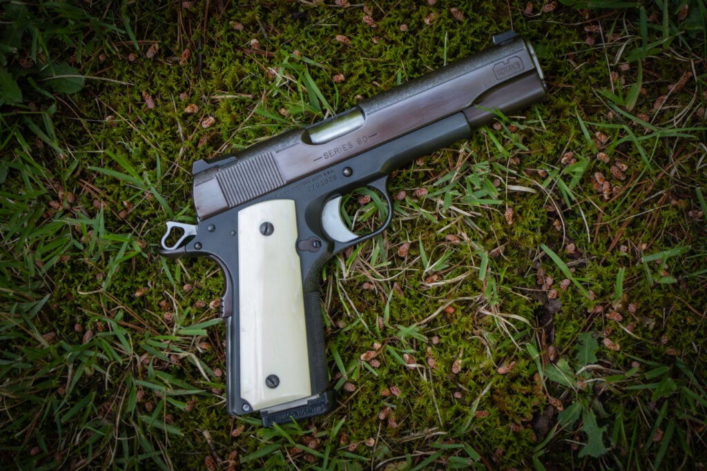 A custom handgun sitting on the grass.
