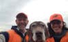 male and female hunters in orange taking a selfie with hunting dog