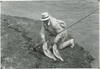 Black and white image of an angler with two large striped bass.