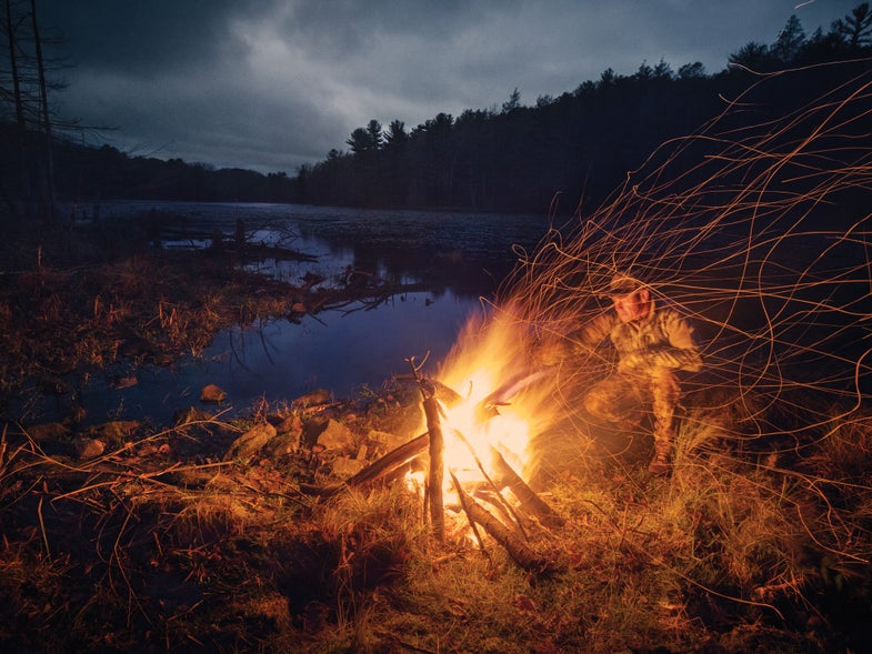 A man building a fire in the wilderness.