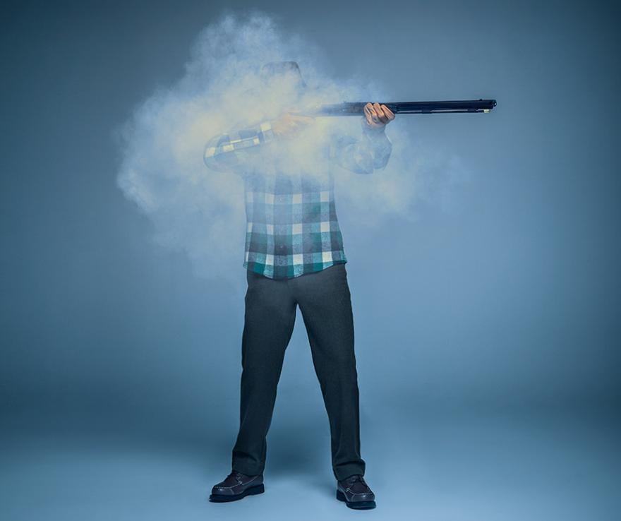 Man shooting a muzzleloader with a cloud of smoke obscuring his face. 