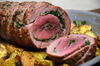 Venison loin roulade stuffed with garlic and herbs served on a large plate.