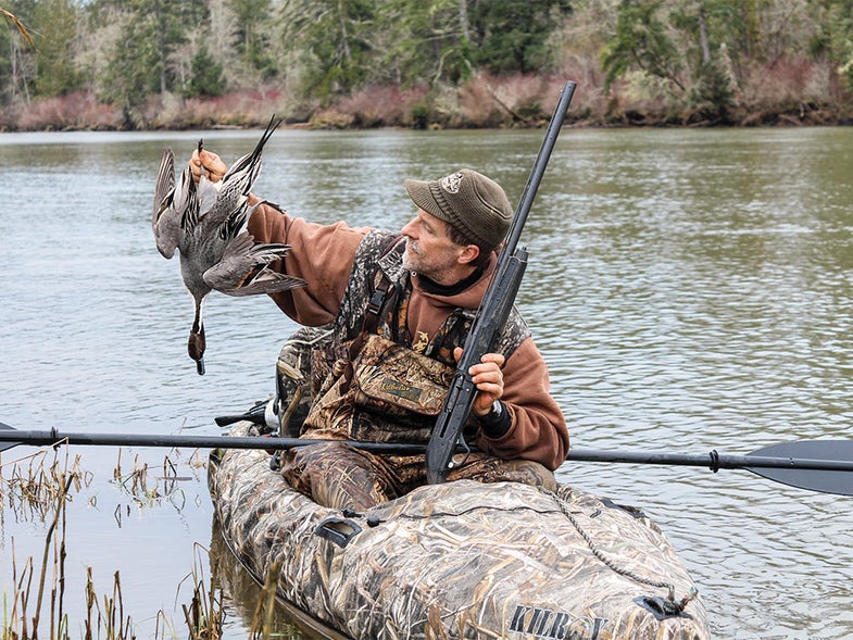 hunter in kayak holding a duck
