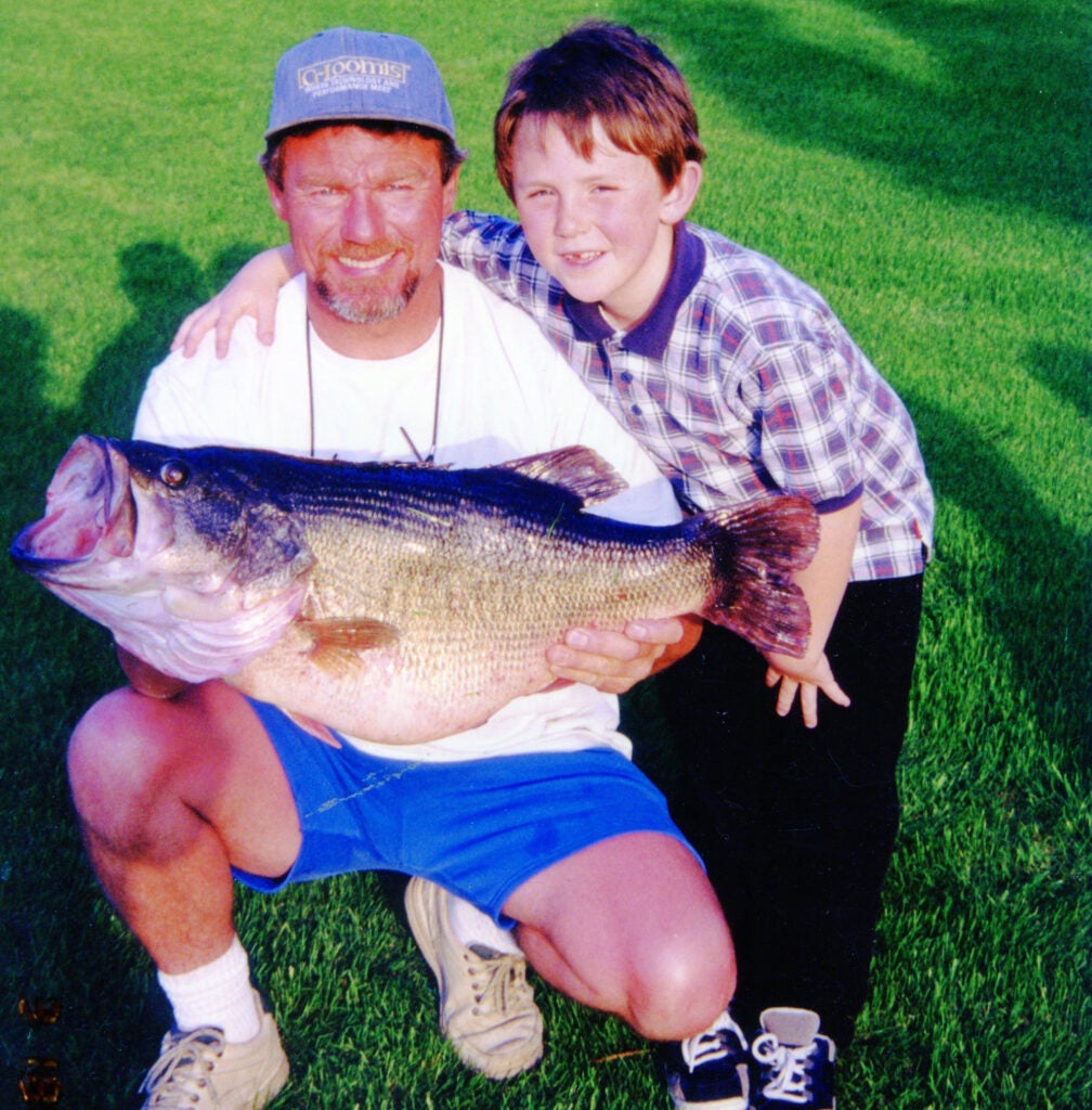 Man and boy posing with a largemouth bass. 