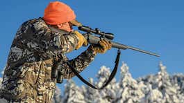 hunter aiming rifle in snowy woods