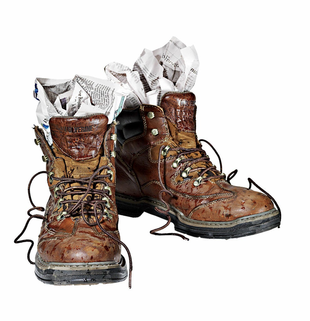 A pair of boots with newspaper stuffed in them.