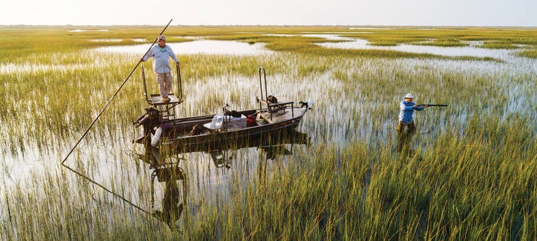 two hunters in a marsh with a john boat