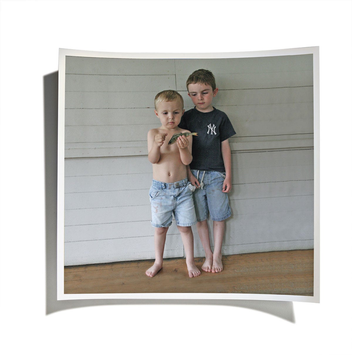 Two young boys holding a fish on a front porch.