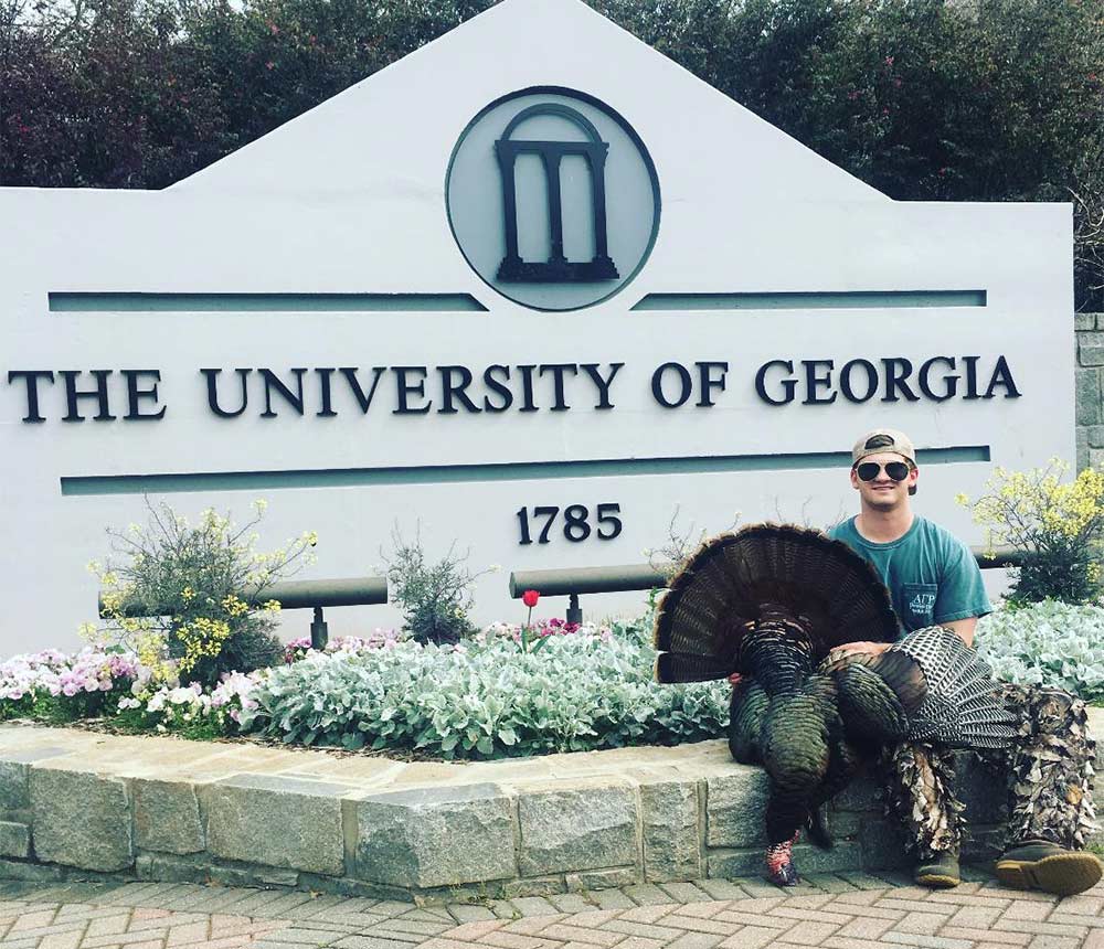 hunter holding a turkey in front of the university of georgia