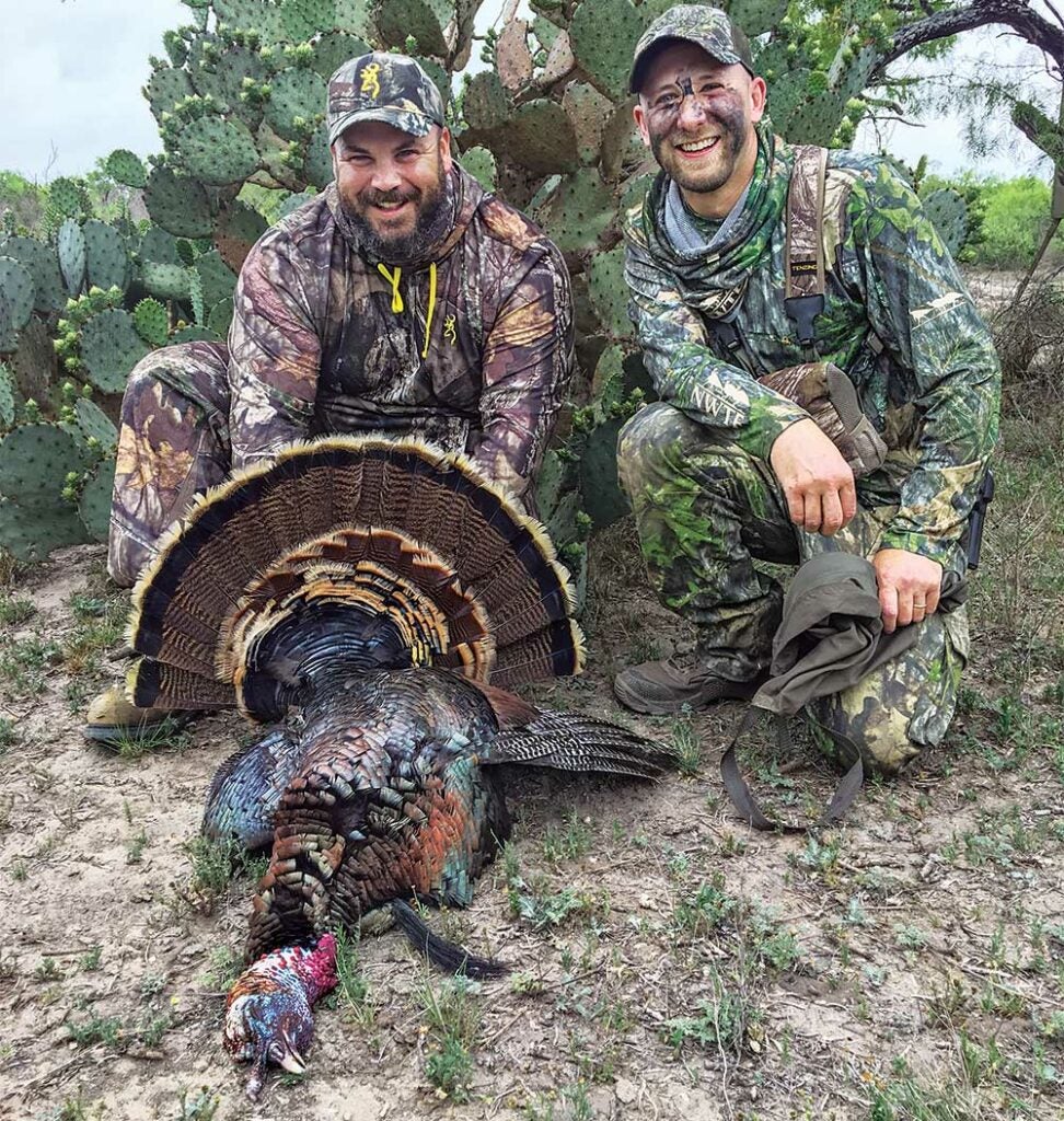 two hunters kneeling behind a turkey