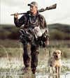 josh miller walking through marsh with hunting dog