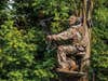 a bowhunter sitting in a treestand while aiming a compound bow