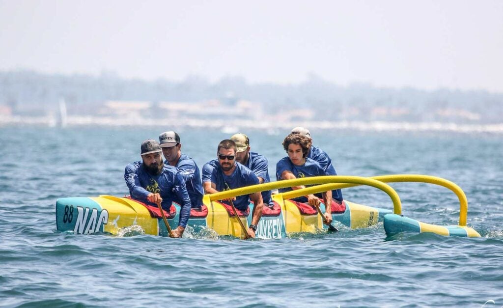 A team paddling a Hawaiian outrigger canoe.