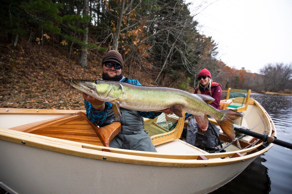 An angler holds up a giant muskie in a Boulder Boat Works drift boat.