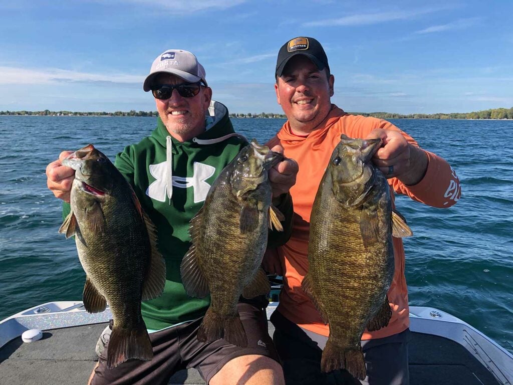 anglers holding up smallmouth bass