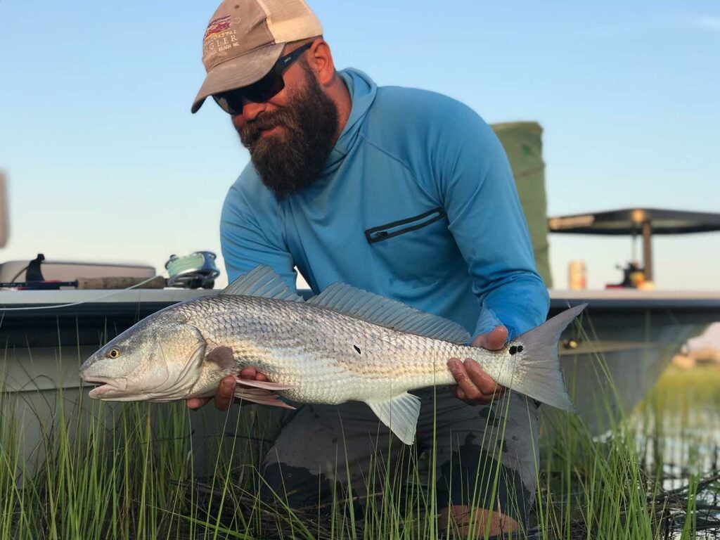 angler holding redfish by boat