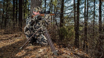 Hunter aiming rifle using Caldwell shooting sticks