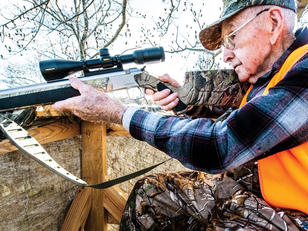 Old hunter aiming a rifle.