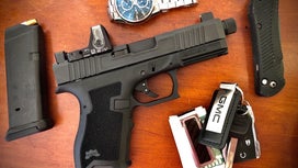 Handgun on table with keys watch and knife.