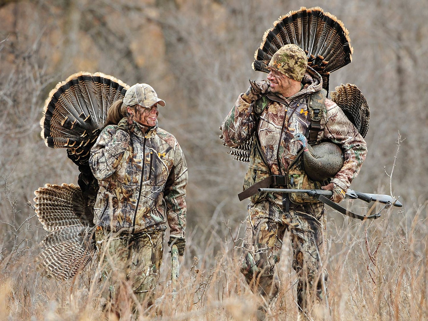 Two turkey hunters walking through a field.
