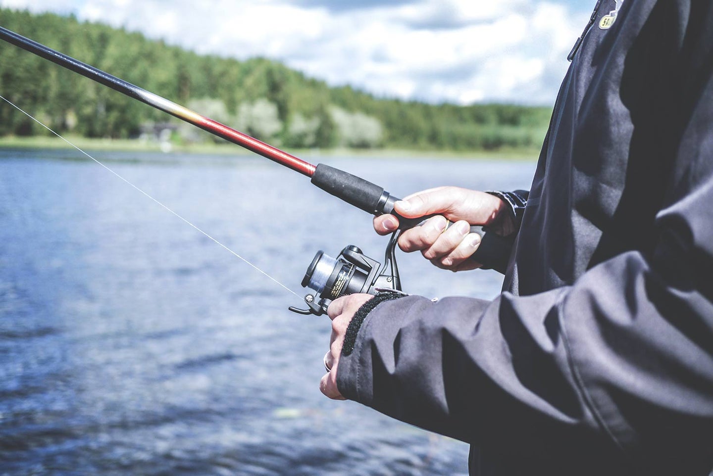 Angler with a fishing reel at a lake.