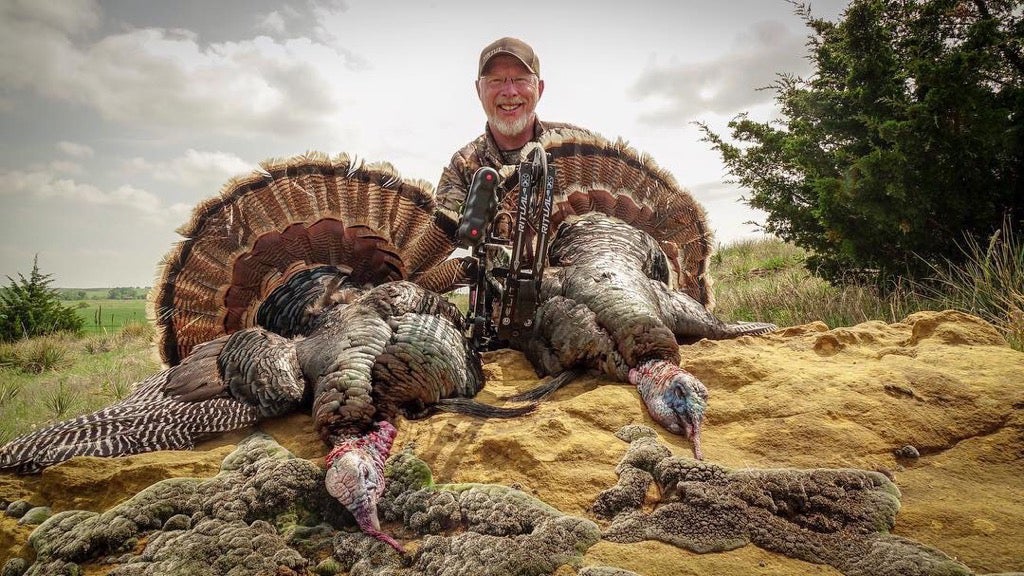 Philip Vanderpool poses with a pair of bow-killed longbeards.