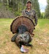 Turkey hunter Will Brantley with a large turkey in a field.