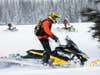 A team of search and rescue personnel riding snowmobiles.