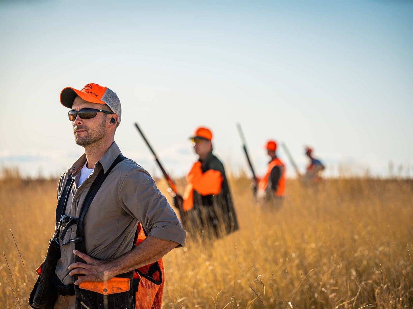 Hunters and guides standing in a brown field.