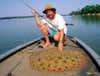 An angler kneeling beside a large discus ray.