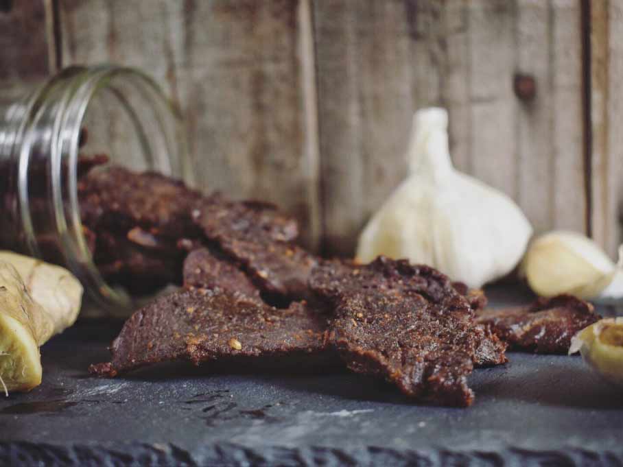 Beef jerky and garlic on a cutting slab.