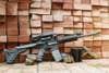 An AR rifle propped up against a pile of bricks.