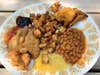 A plate of northern pike that has been deep fried next to potatoes, beans and various sides.