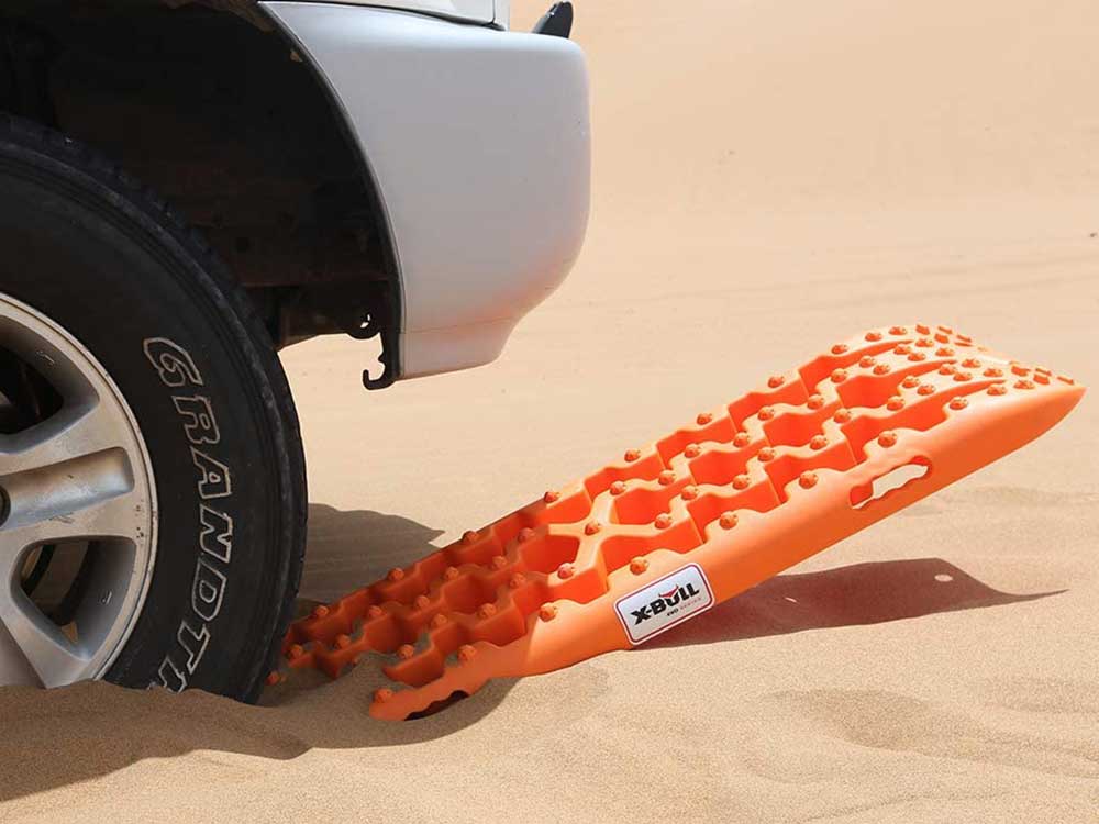 Traction board with SUV in sand.