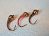 Three copper fly lure hooks on a white table.