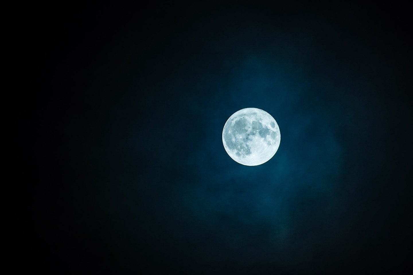 A full moon in the night sky with no stars.