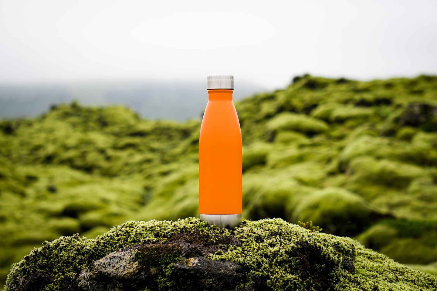 Orange water bottle on a mountain top