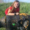 A young girl shows off a group of arrows tightly grouped in the target of a deer decoy.
