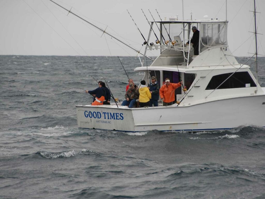 A group of anglers standing on the deck of a sport fishing boat.