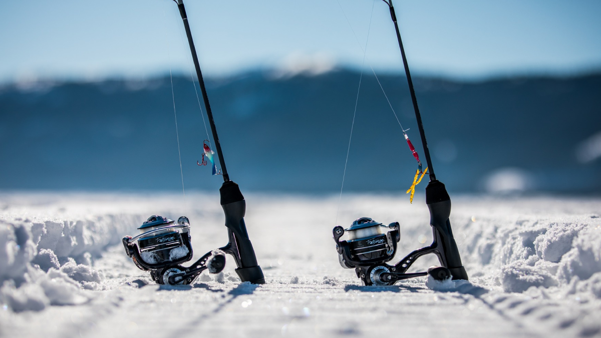 Clam ice fishing lures and reels sitting on frozen lake