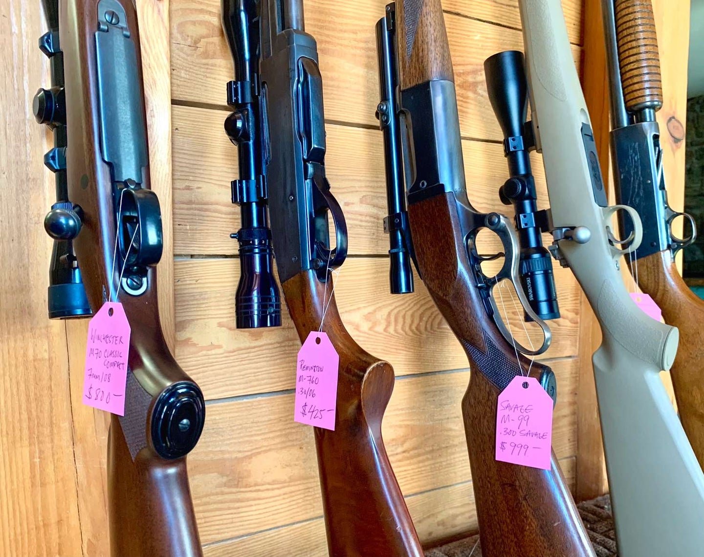 A lineup of rifles tagged with sales tags.