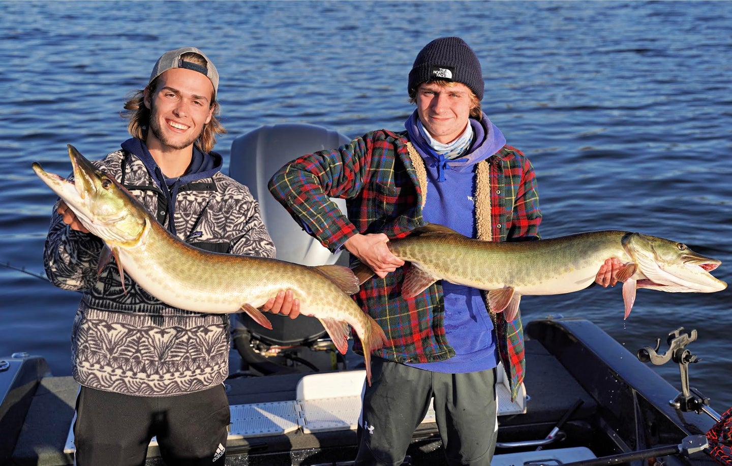 Two anglers holding up large muskie fish.
