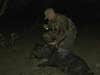 A hunter kneels next to a dead hog at night.