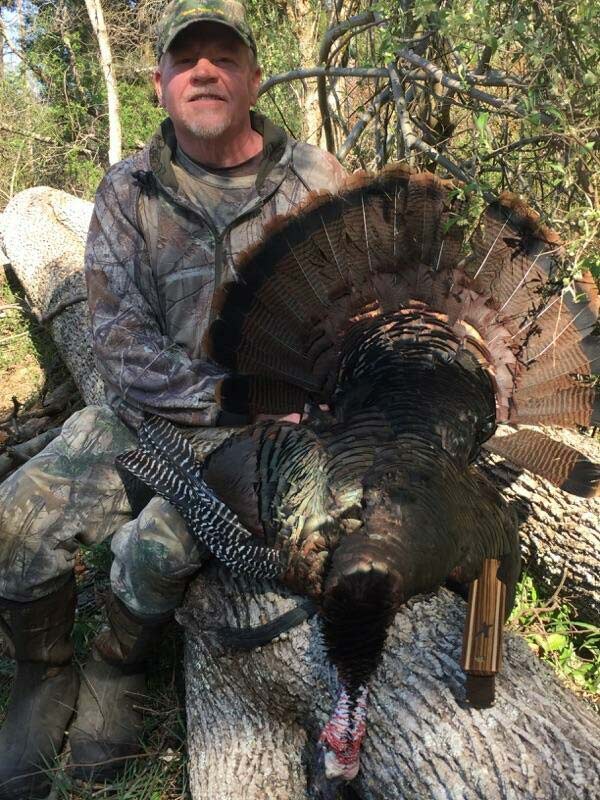 A hunter next to a turkey.