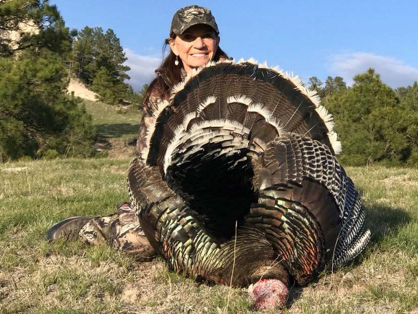 A hunter poses next to a large turkey.