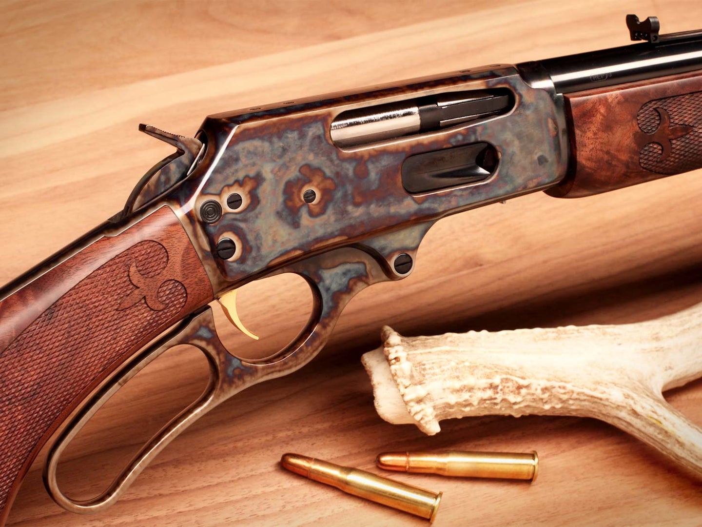A close up image of a lever-action rifle on a wooden floor.
